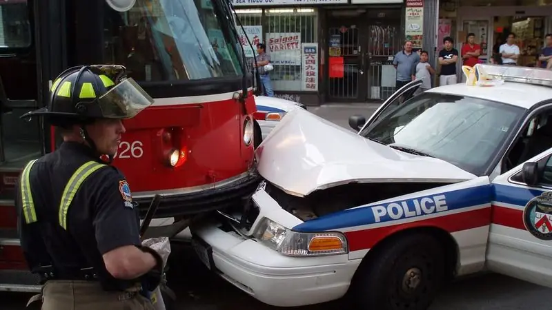 First responder at a collision scene with a damaged police cruiser — choosing a car accident lawyer in Meriden, CT